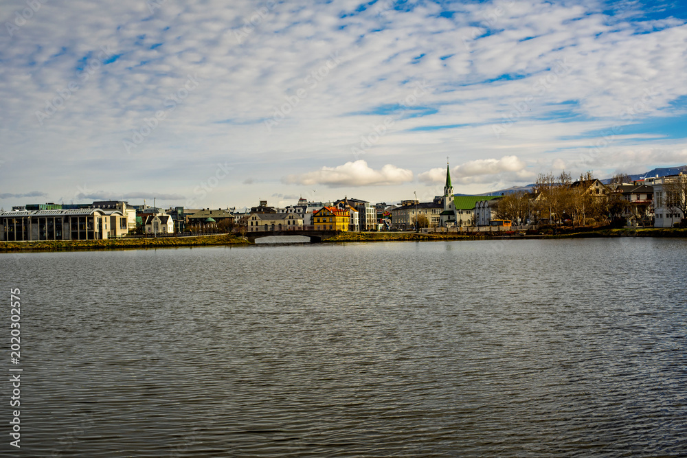 Obraz premium Reykjavik cityscape across Tjornin lake with Frikirkjan church and colorful houses, Iceland
