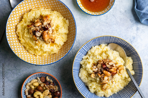 Delicious healthy breakfast: millet porridge cooked with coconut milk and toped up with caramelised mixed nuts and maple syrup