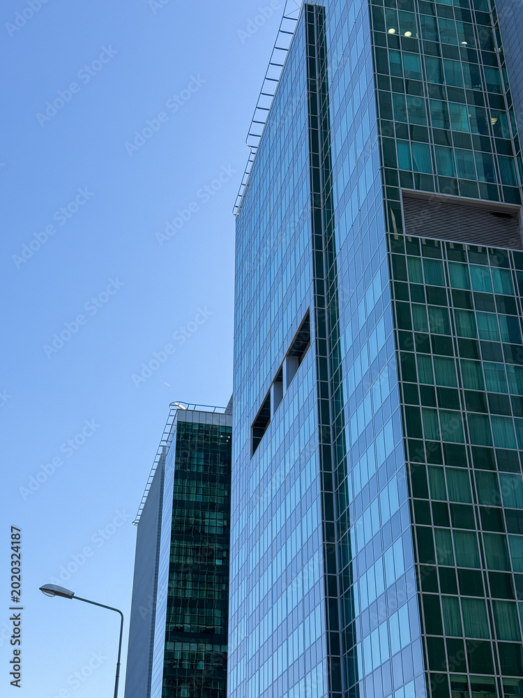 Naklejka premium Skyscrapers in the city and blue sky background. Minimalistic architecture made of glass, tall buildings, business and finance, construction industry.
