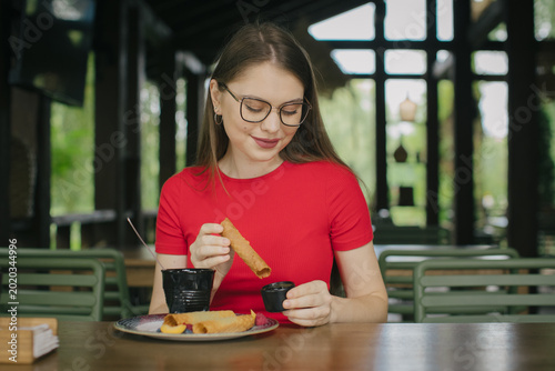 Fényképezés Young woman dipping wafer roll in chocolate sauce