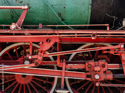 Bild auf Leinwand Close-Up Of Red Steam Locomotive Wheels And Mechanism On Vintage Green Boiler