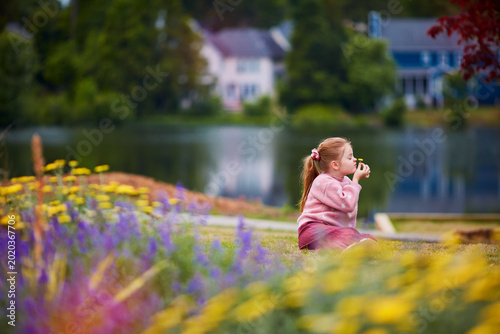 Child Enjoying Nature and Smelling Wildflowers Near Calm Suburban Lake on Summer Day. Tansy Bloom