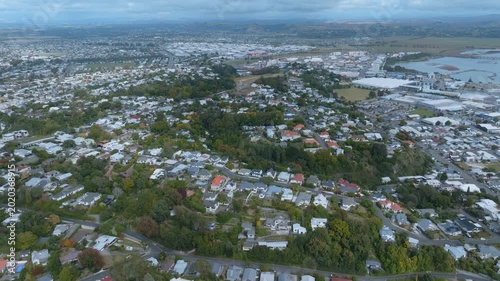 Aerial view of residential homes and commercial buildings in Napier, New Zealand. The city is nestled amongst rolling hills and a beautiful coastline.
