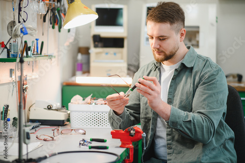 Man spectacles repair using screwdriver in optical workshop