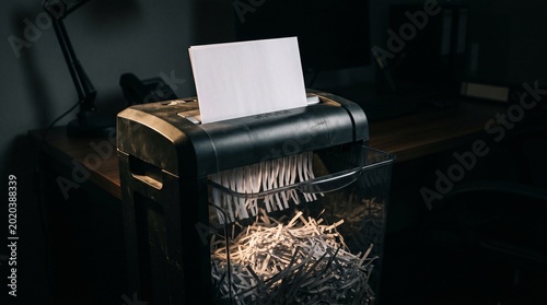 Office paper shredder machine destroying sensitive white document.