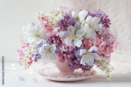 Foto Spring bouquet of lilacs, hyacinths, bird cherry and apple blossoms in a cup on
