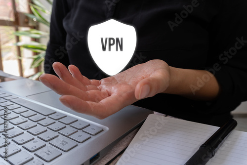Hand holds protective shield above laptop. Shield reads 