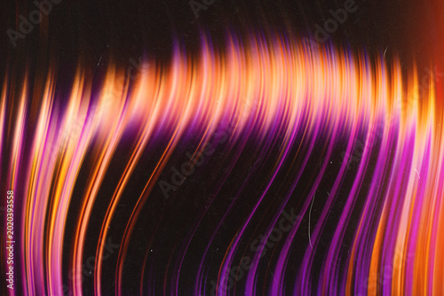 Vibrant purple and orange curved light streaks creating a dynamic abstract background with film texture