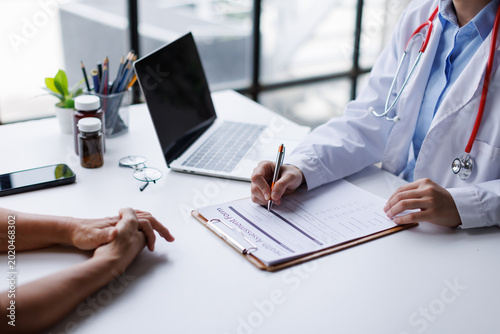 Foto Doctor discussing medical treatment plan and writing prescription for patient du