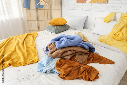 Pile of clothes on bed in m...