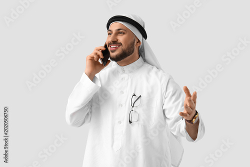Foto Arab businessman talking by mobile phone on light background