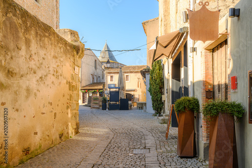 A narrow cobblestone street of shops and cafes in La Cite' within the fortified walls of the historic castle of Carcassonne in France.
