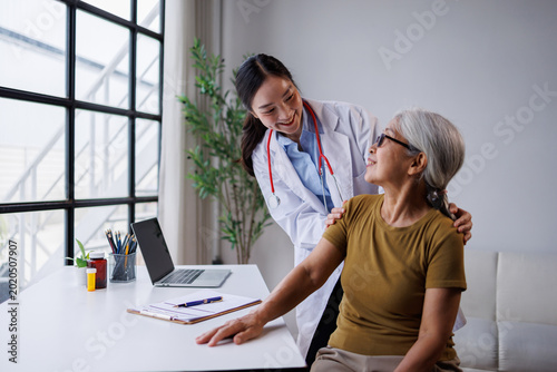 Young asian woman doctor providing compassionate care and support to an elderly female patient during a routine medical checkup in a modern clinic setting