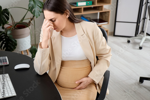 Tired young pregnant busine...