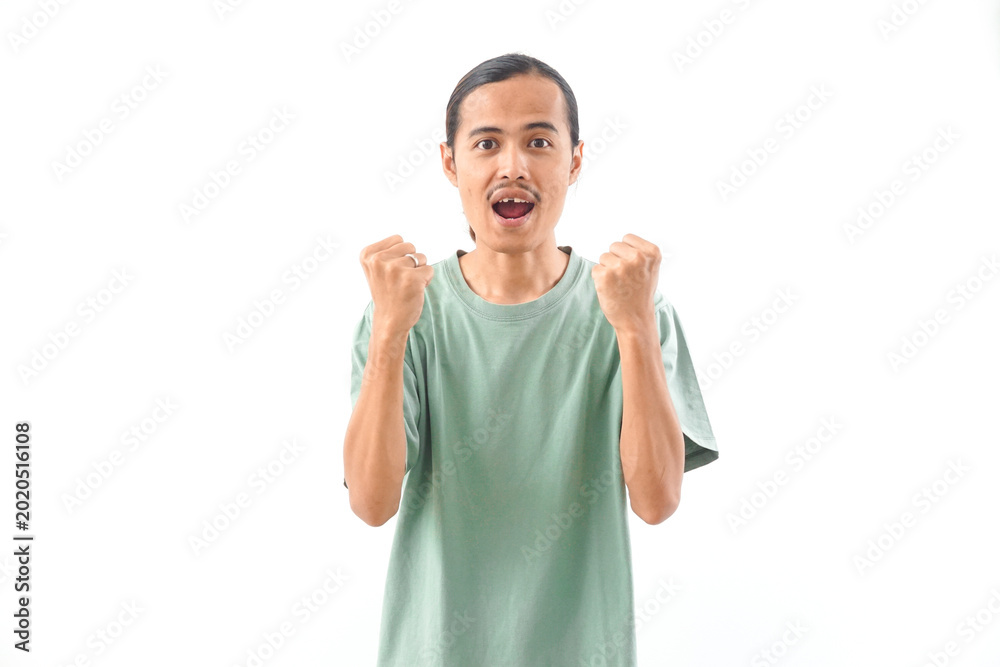 Naklejka premium young handsome Indonesian, Asian man in green shirt positive expression, joyful and exciting isolated on white background. Happy adorable glad man rejoices success
