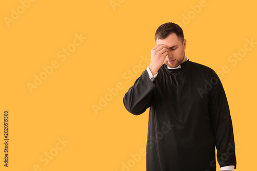 Bild auf Leinwand Young priest cross oneself on yellow background
