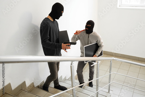Photos Male thieves with stolen valuables escaping in stairway