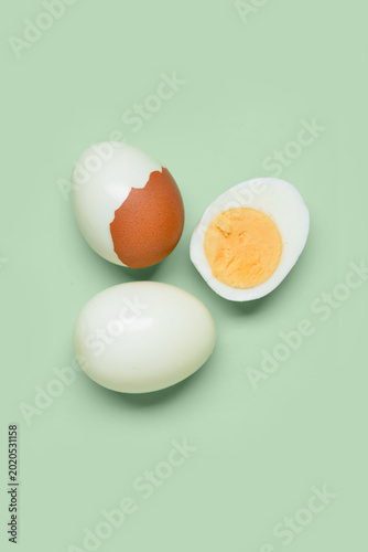 Tasty boiled eggs with half on green background