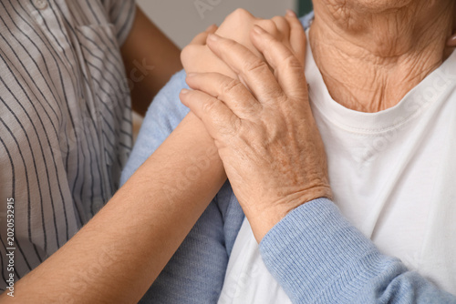 Young woman with her grandmother holding hands at home  closeup