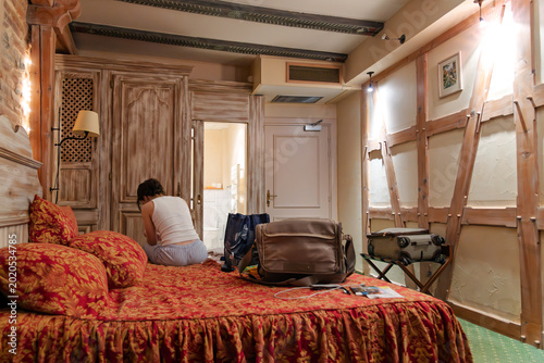 A young woman settles into a historic hotel room in the medieval center of a European village.