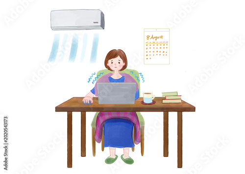 Foto 冷房の効いた部屋で寒さに耐えながら机でパソコンを開き仕事をする女性