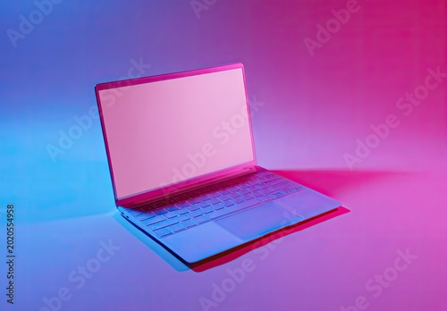 Modern laptop bathed in pink and blue light, open and facing upward