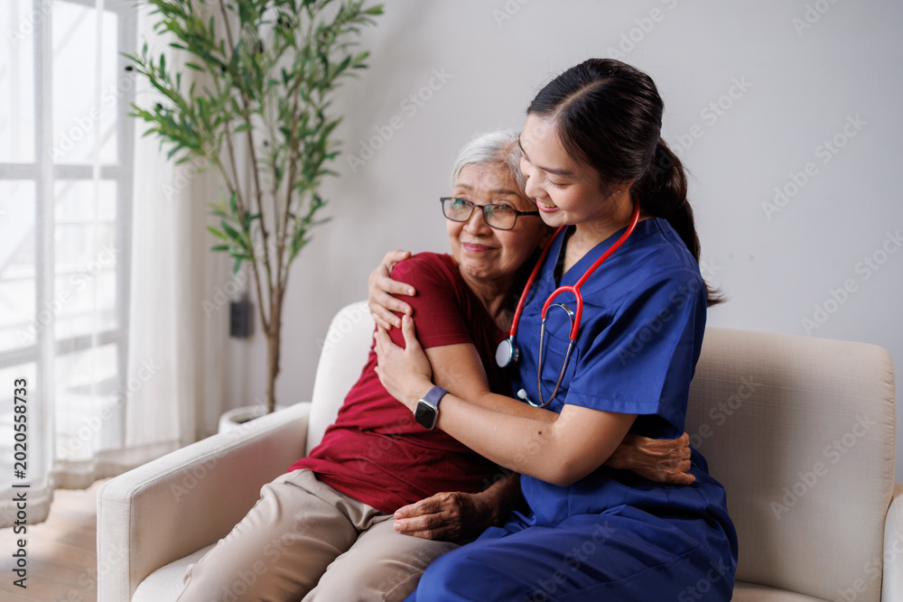 Naklejka premium Professional caregiver expressing empathy and providing compassionate support, hugging an elderly woman on a sofa during an in-home visit or at a care facility