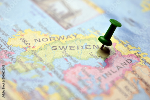 Macro Close-Up Green Push Pin Highlighting Sweden on Blurred World Map Travel Concept Background