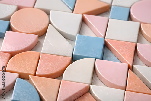 Colorful geometric tiles composed of pastel pink blue white and peach shapes with smooth surfaces arranged in a seamless pattern for modern decor or design projects