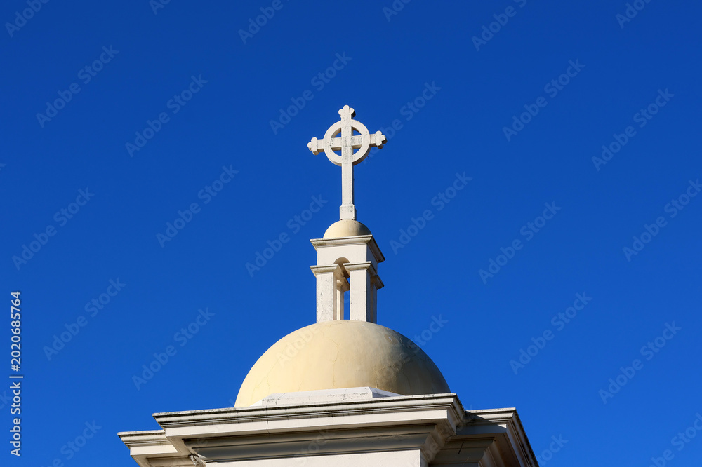 Φωτογραφία White stone Celtic cross atop a church dome against a clear blue sky