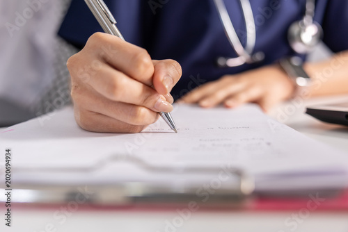 Medical doctor prescription writing stethoscope healthcare clinic patient paperwork consultation, close up view hand holding pen while doctor uniform write prescription medical form with