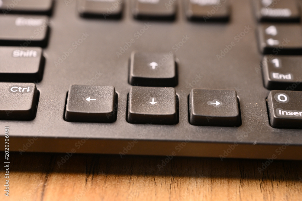 Fototapeta premium Angled Top View Macro Close-Up Black Computer Keyboard Highlighting Down Arrow Key on Blurred Tech Background