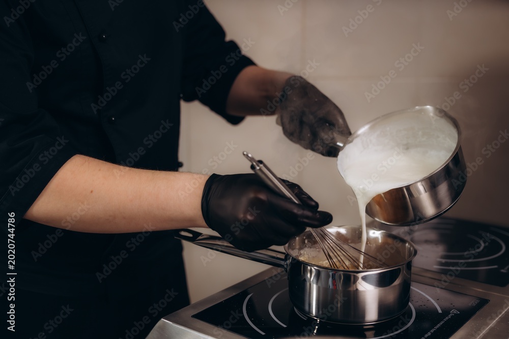 Fotografi Chef preparing cream sauce pouring milk in saucepan