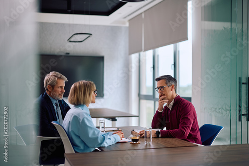 Corporate office managers having job interview with male candidate.