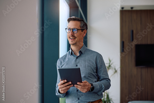 Foto Happy entrepreneur using touchpad while working in office.