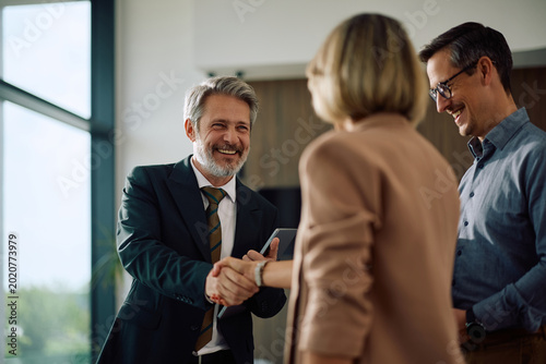 Bild auf Leinwand Happy insurance agent shaking hands with couple after successful meeting in office