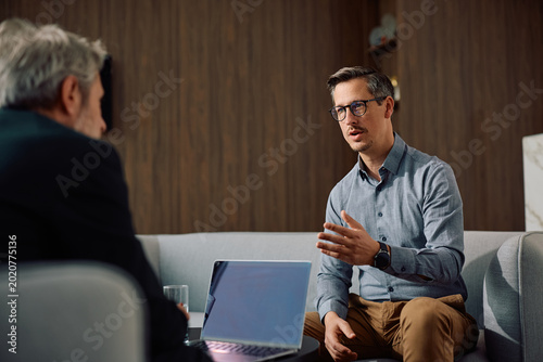 Male entrepreneur communicating with CEO during business meeting in office.