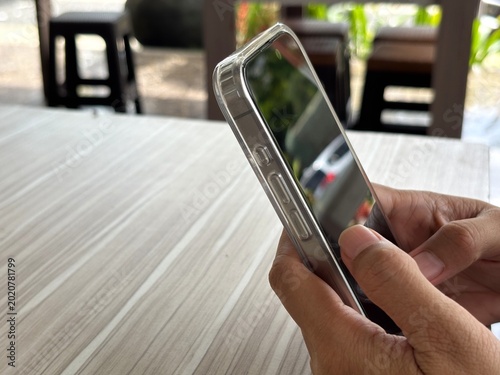 Foto An Asian woman holds a cell phone with a specially designed tempered glass screen protector that uses polarizing optical coating technology to make it difficult to spy on