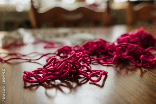 Pile of red yarn sits on table with sewing measure tape in background
