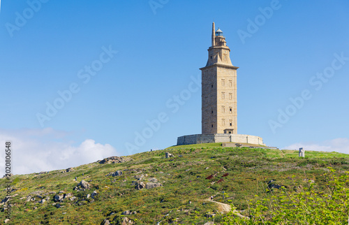 The Tower of Hercules ancient Roman lighthouse on a green hill under blue sky in A Coruña Galicia, Spain