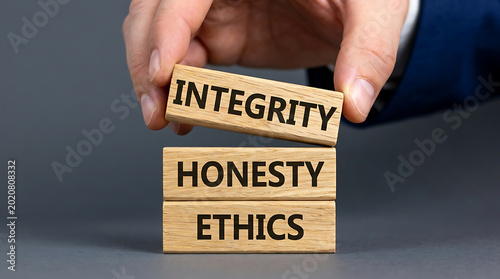 Businessman hand placing a wooden block with the word integrity on top of honesty and ethics to represent core corporate values and moral principles.