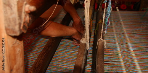 Close up of a Skilled artisan's hands weaving vibrant, colorful textile on a traditional loom