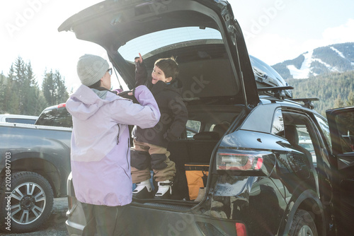 Mother helping her excited son get ready to ski