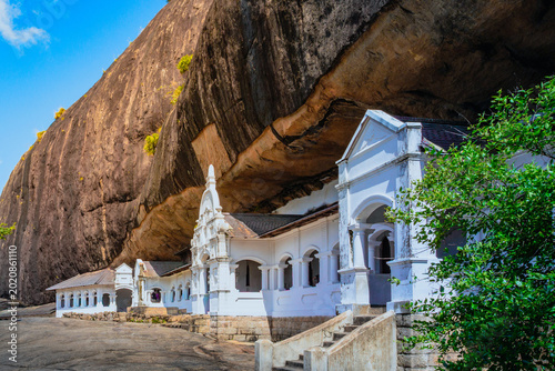 Rangiri Dambulla Cave Temple in Sri Lanka beneath giant rock formation with ancient Buddhist monastery architecture and historic courtyard. Famous Sri Lanka heritage and cultural travel destination
