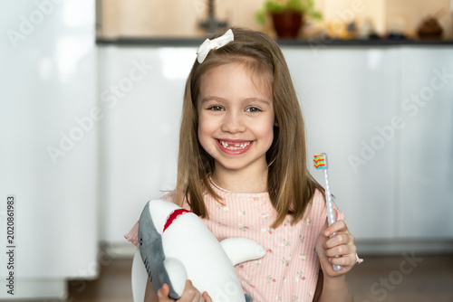 Photos Little happy toothless girl with toothbrush looks at camera and laughs