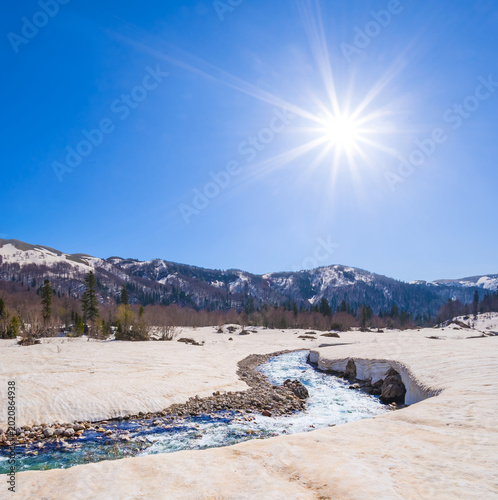 Foto river flow through the snowbound mountain valley at the sunny spring day