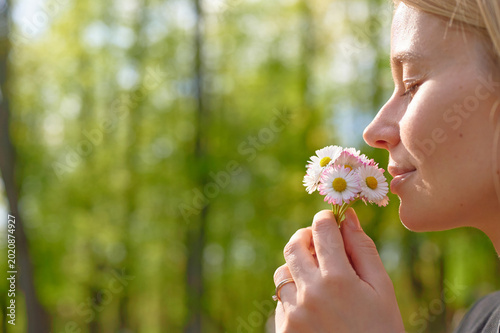 Foto Woman smelling daisies in a forest