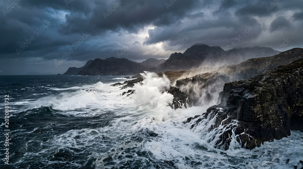Fototapeta premium Dramatic ocean waves crash against rugged rocky coastline under stormy skies.