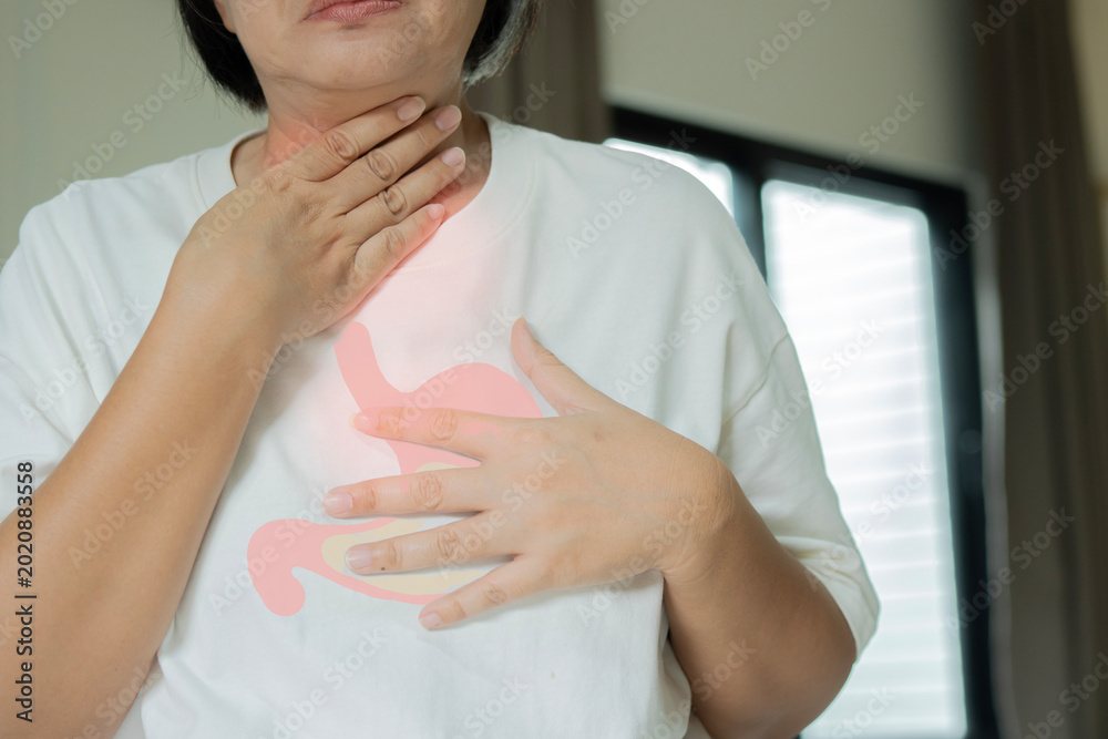 Φωτογραφία Mature Asian woman standing in livingroom and having an chest pain indoors