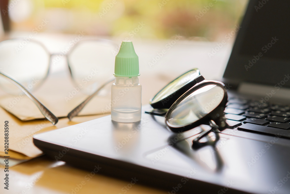 Photography Eyeglasses and eye drop bottle on laptop at desk workplace